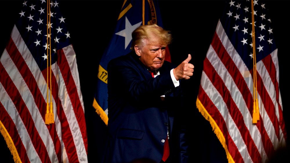 Image: Former U.S. President Donald Trump on stage giving a thumbs-up.