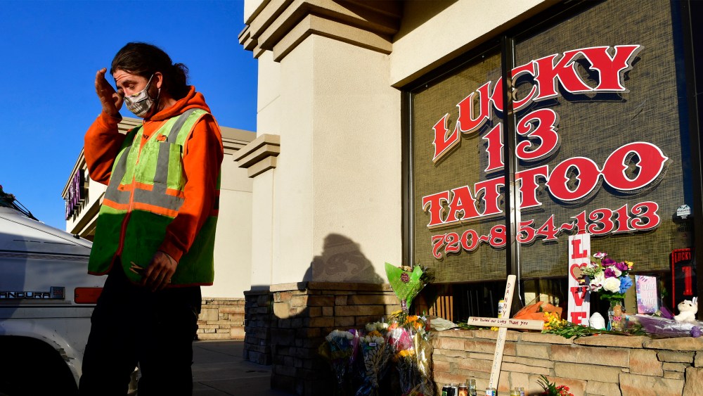 Image: Dylan Danielson wipes away a tear near on a small memorial outside Lucky 13 Tattoo and Body Piercings.