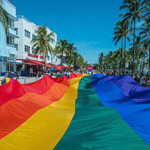 Image: A multi-colored pride flag flies as people participate in the Pride Parade in Miami.