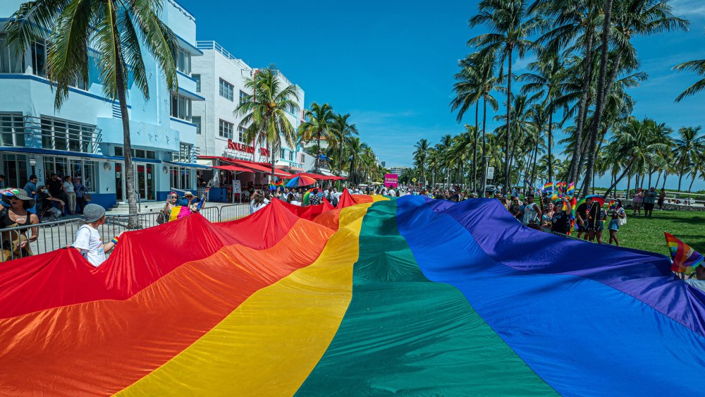Image: A multi-colored pride flag flies as people participate in the Pride Parade in Miami.