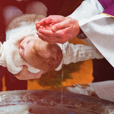 Image: Photograph of a priest is baptizing a baby in a church with a red color overcast.