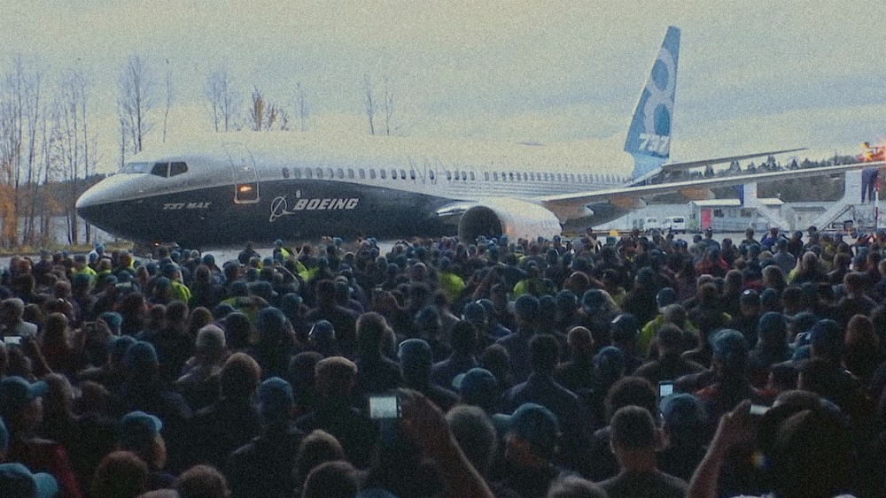 Image: Screengrab from the Netflix documentary,"Downfall: The Case Against Boeing.". A crowd of people around an airplane.