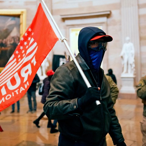 Image: A protestor holding a red flag that reads,"Trump" inside the Capitol in Washington, D.C.