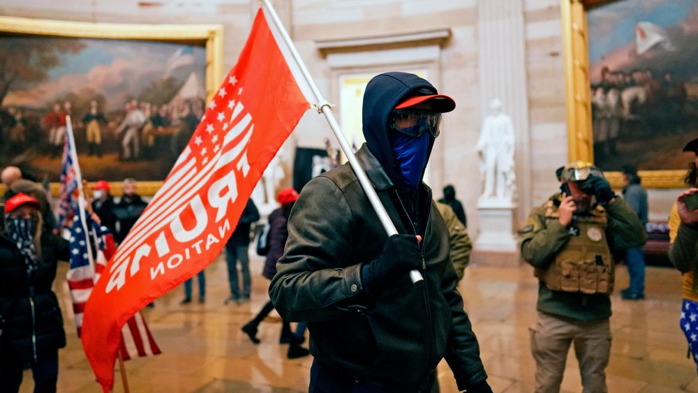 Image: A protestor holding a red flag that reads,"Trump" inside the Capitol in Washington, D.C.