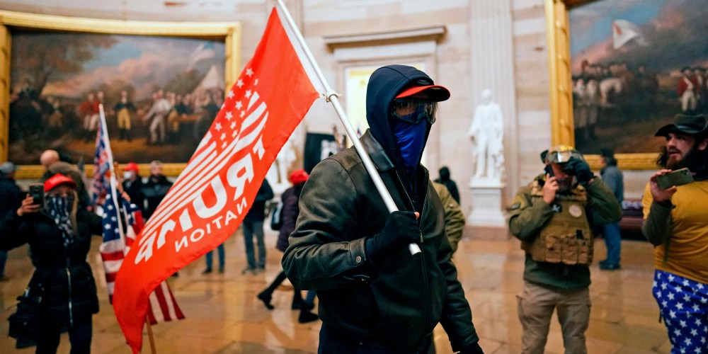 Image: A protestor holding a red flag that reads,"Trump" inside the Capitol in Washington, D.C.