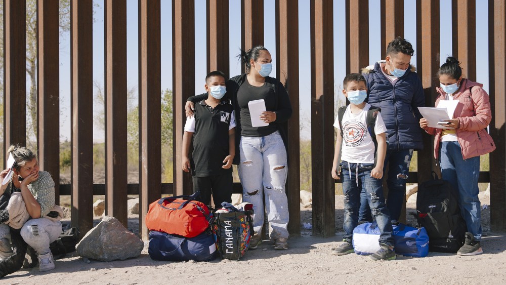 Image: Asylum seekers wait to be processed by the Customs and Border Protection, next to the border wall between Mexico and the U.S in Yuma, Arizona.