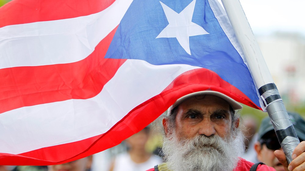 Image: A man carrying a Puerto Rican flag.
