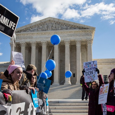 Image: Pro-choice advocates and anti-abortion advocates rally outside of the Supreme Court. Some of the visible signs read,"#TeamLife", "Protect Women, Protect Life" and "Don't agree with abortion? Don't have one".