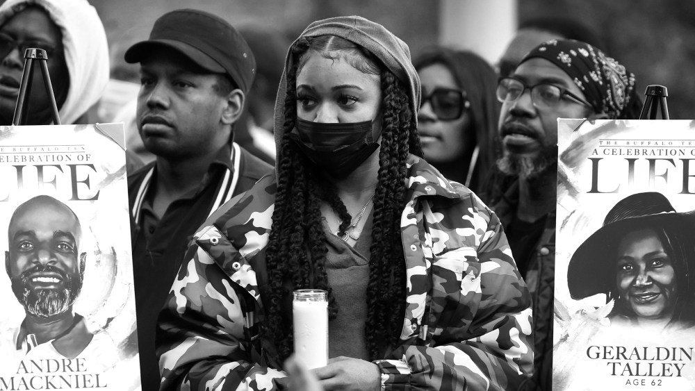 Image: People hold candles and two posters that show portraits and have text that read,"A celebration of life".