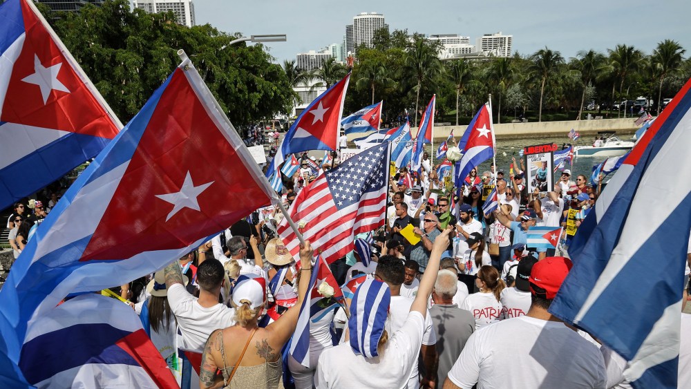 Image: People waving Cuban flags along with some people waving the American flag.