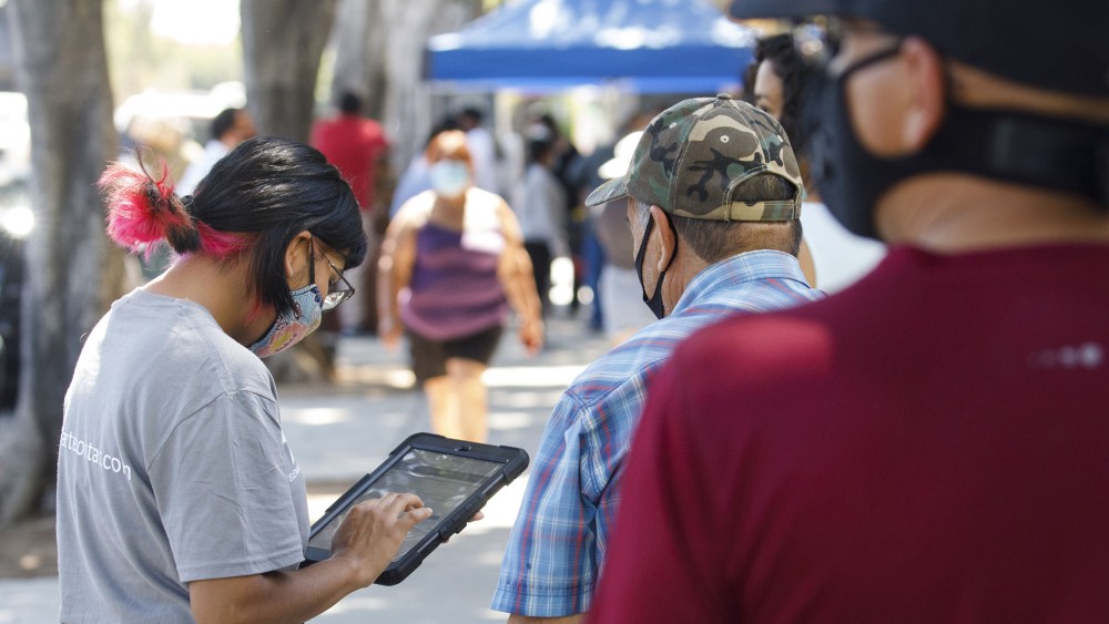 Image: A youth ambassador conducting a census interview with people walking by.