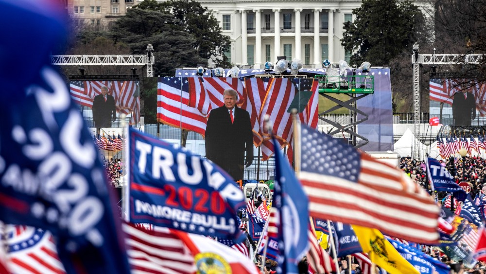 Image: Audience at the crowd waving flags while  Donald Trump is on stage.