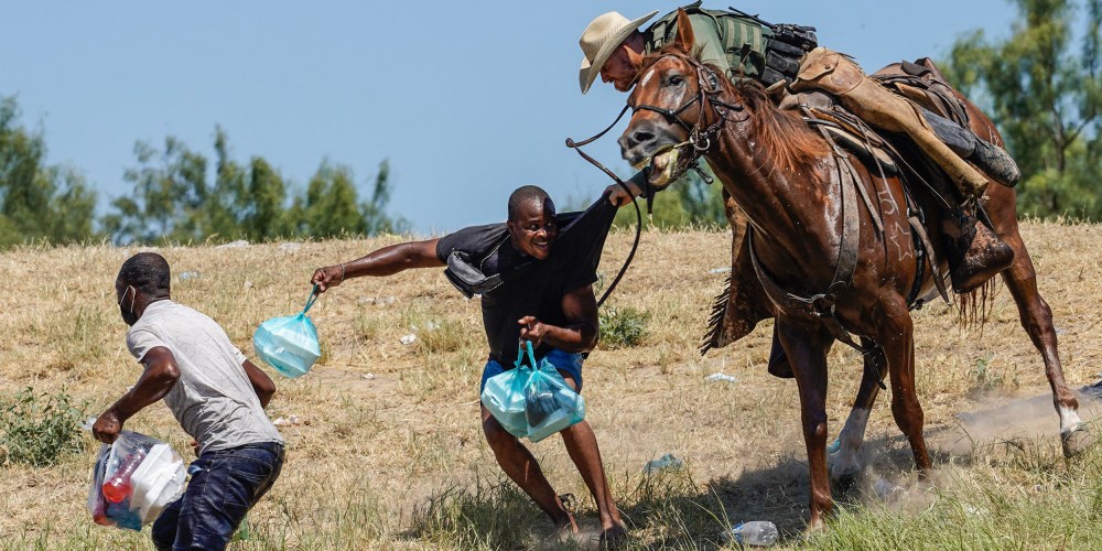 Image: A border patrol agent trying to stop a migrant carrying a food packet.