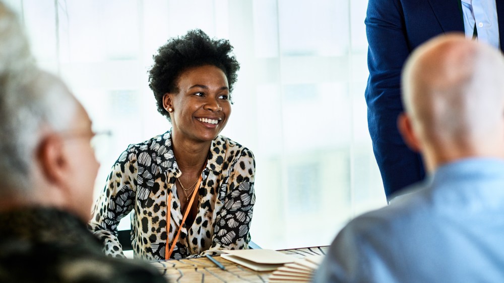 Candid portrait of mid adult black businesswoman smiling in meeting