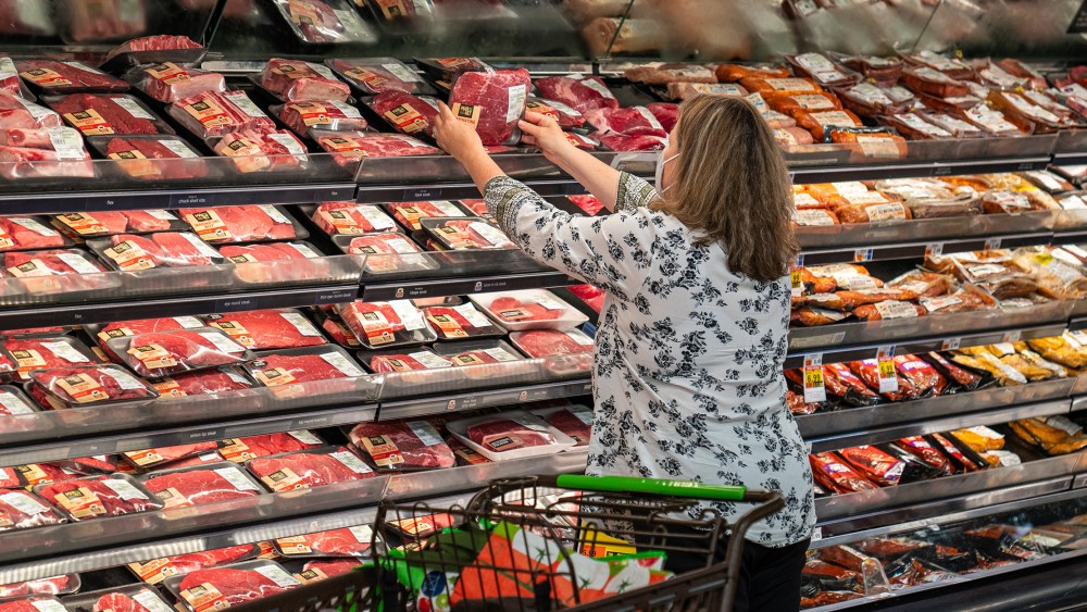 Image: A shopper in the meat section at a supermarket.