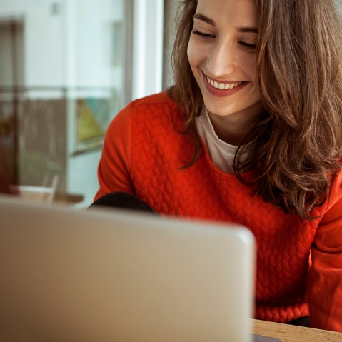 Smiling young woman using laptop on balcony