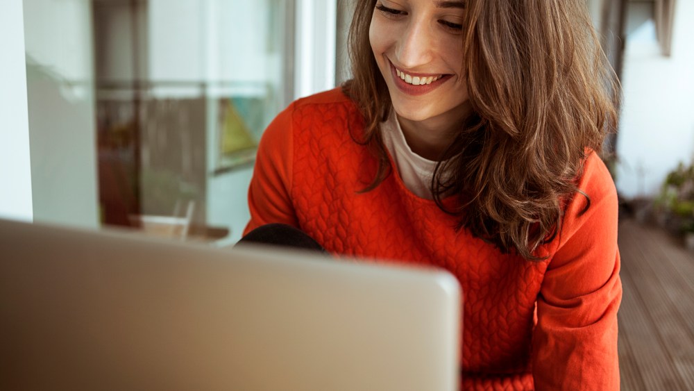 Smiling young woman using laptop on balcony