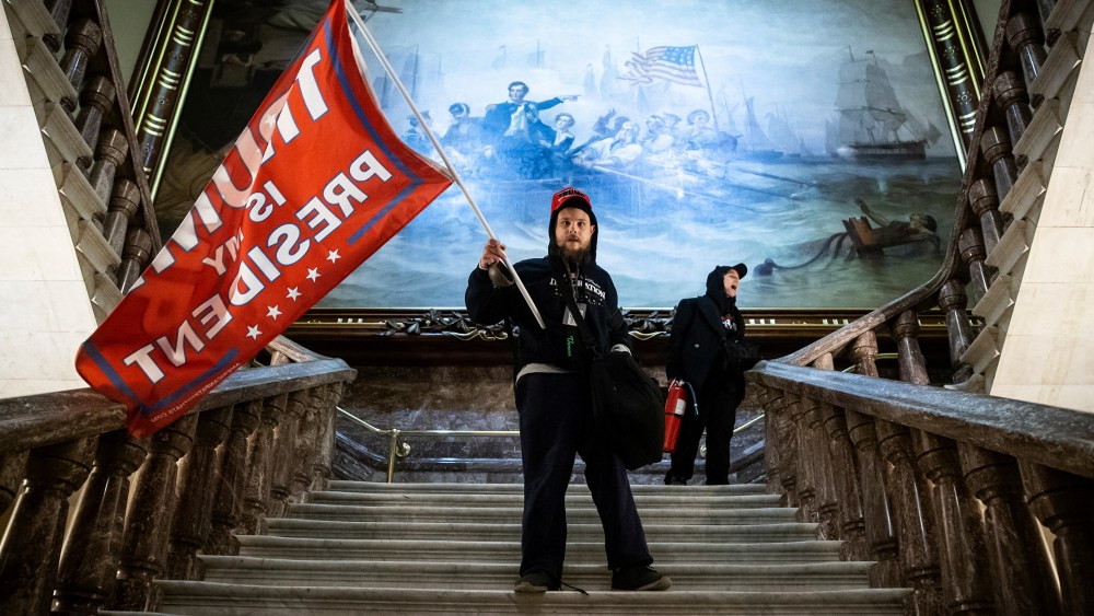 Image: A person holding a red flag that reads,"Trump is my president".