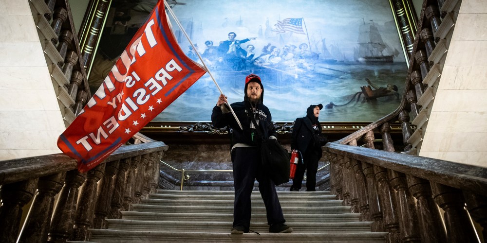 Image: A person holding a red flag that reads,"Trump is my president".