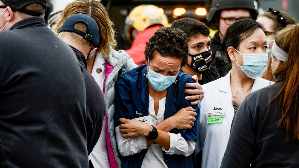 Image: A woman consoles a King Soopers pharmacy technician after a shooting at the grocery store in Boulder