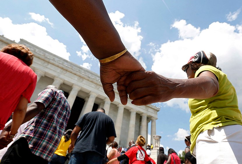 Marchers hold hands in prayer at the 50th anniversary ceremony of the 1963 March ceremony at the Lincoln Memorial on Washington