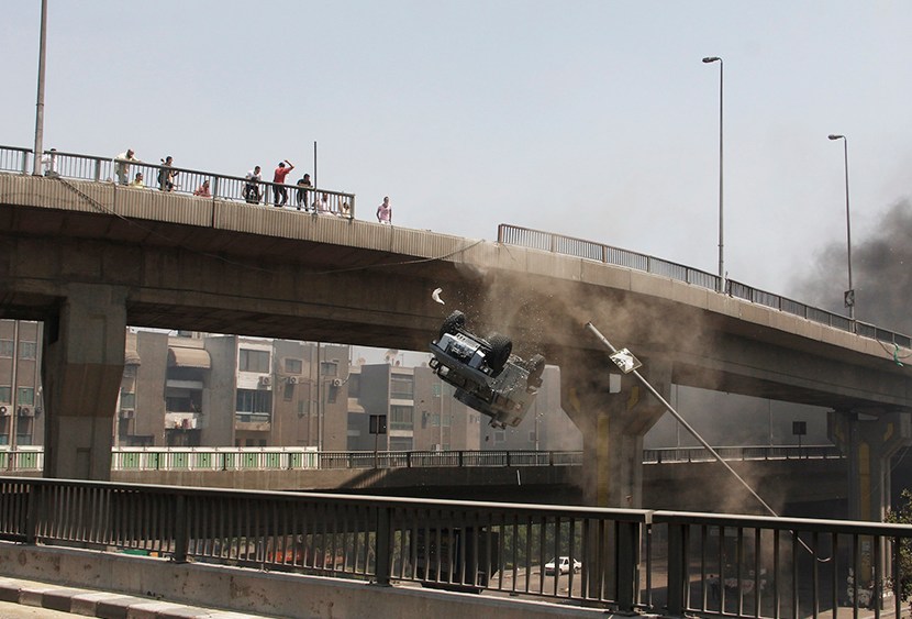 A police vehicle is pushed off of the 6th of October bridge by protesters close to the largest sit-in by supporters of ousted Islamist President Mohammed Morsi in the eastern Nasr City district of Cairo, Egypt, Wednesday, Aug. 14, 2013.  (Photo by...