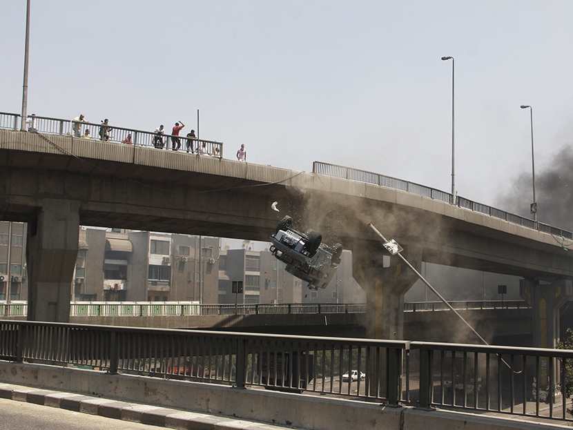 A police vehicle is pushed off of the 6th of October bridge by protesters close to the largest sit-in by supporters of ousted Islamist President Mohammed Morsi in the eastern Nasr City district of Cairo, Egypt, Wednesday, Aug. 14, 2013. (Photo by...