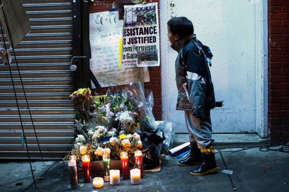 A child reads posters at the makeshift memorial where Eric Garner died during an arrest in July, at the Staten Island borough of New York, N.Y. on Dec. 3, 2014. (Photo by Eduardo Munoz/Reuters)