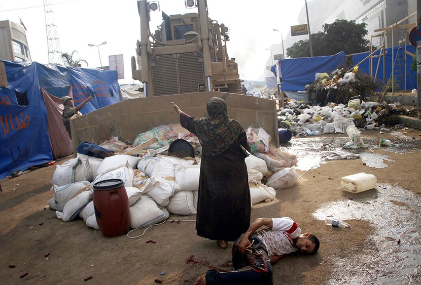 An Egyptian woman tries to stop a military bulldozer from hurting a wounded youth during clashes that broke out as Egyptian security forces moved in to disperse supporters of Egypt's deposed president Mohamed Morsi in a huge protest camp near Rabaa al...