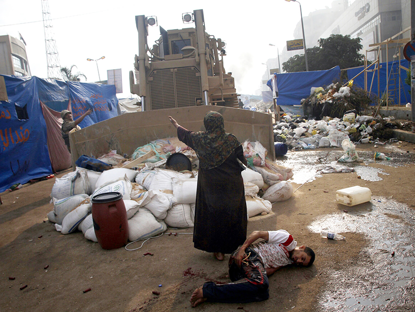 An Egyptian woman tries to stop a military bulldozer from hurting a wounded youth during clashes that broke out as Egyptian security forces moved in to disperse supporters of Egypt's deposed president Mohamed Morsi in a huge protest camp near Rabaa al...