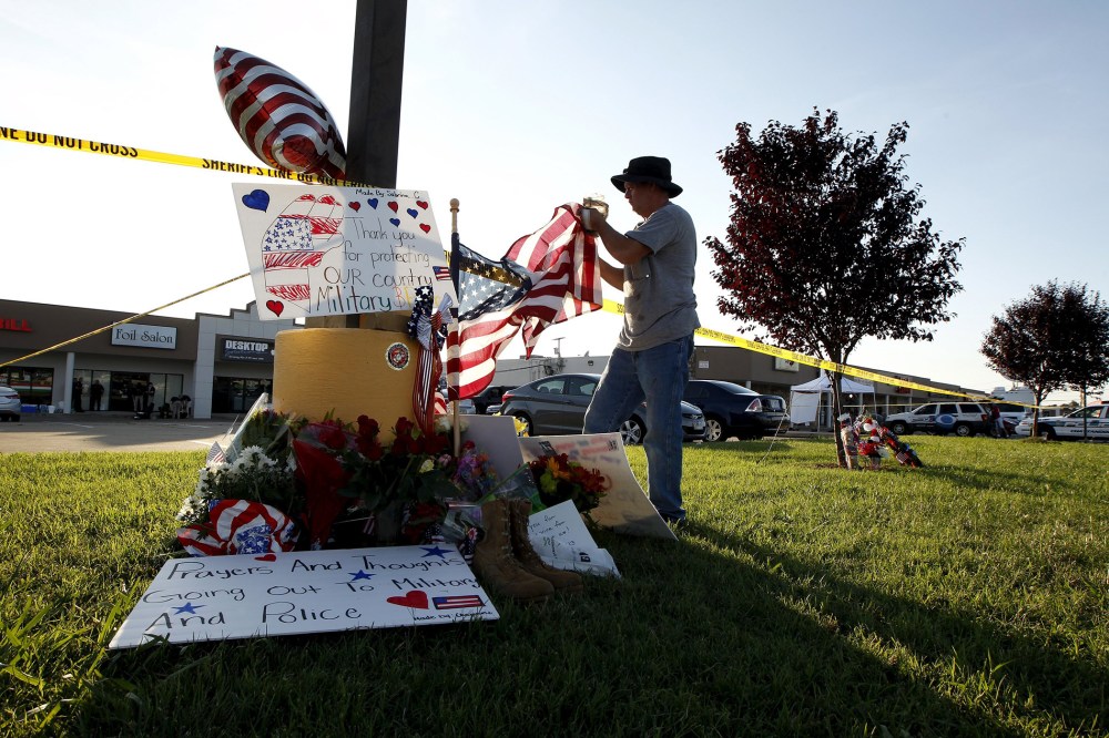 David Croft fixes the U.S. flag at a growing memorial in front of the Armed Forces Career Center in Chattanooga, Tenn., July 16, 2015. (Photo by Tami Chappell/Reuters)