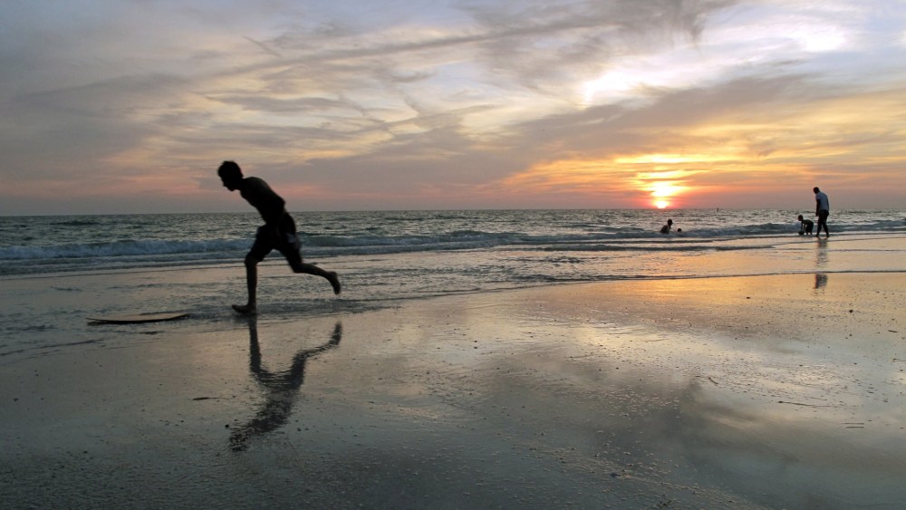 A beachgoer jumps on his 'boogie board' at sunset on a beach in Bradenton, Florida, May 18, 2010.