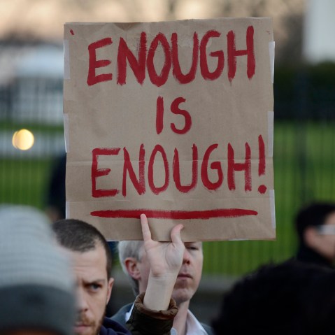 A gun control supporter holds up a sign that reads 'Enough is Enough' during a candlelight vigil for victims of the Sandy Hook Elementary School shooting, outside the White House (Photo by Michael Reynolds/EPA)