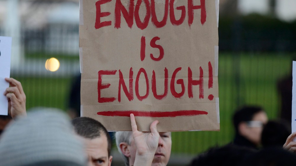 A gun control supporter holds up a sign that reads 'Enough is Enough' during a candlelight vigil for victims of the Sandy Hook Elementary School shooting, outside the White House (Photo by Michael Reynolds/EPA)