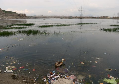 A duck swims among trash thrown into a dam in Kabul during World Earth Day on April 22, 2013. (Photo By: Massoud Hossaini/AFP Photo)