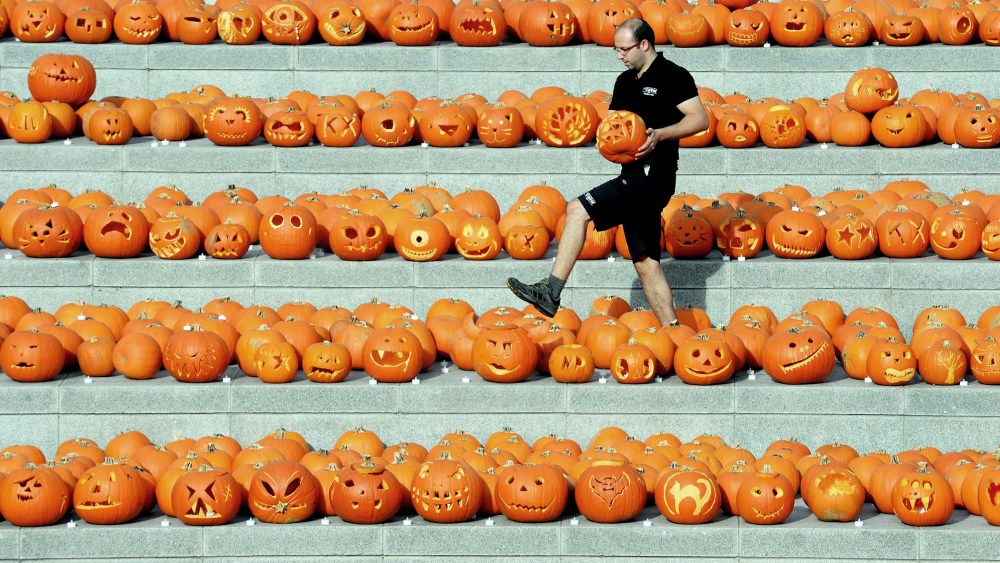 A worker carries a carved pumpkin amongst some of the 3000 pumpkins in Granary square nest to Regents canal in central London, England, Oct. 31, 2014.