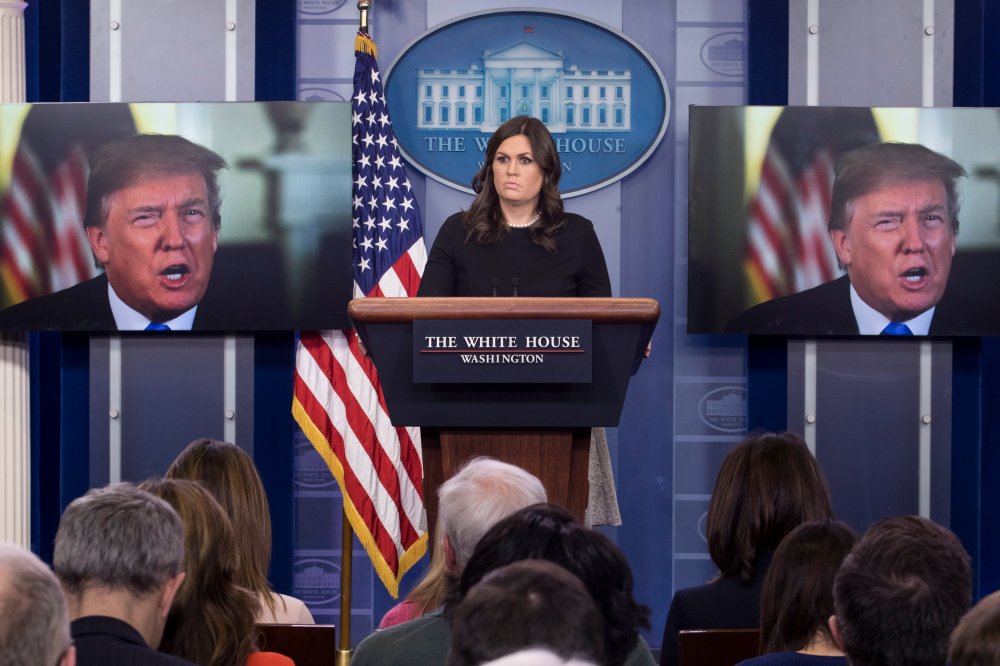 White House Press Secretary Sarah Huckabee Sanders stands beside monitors showing US President Donald J. Trump delivering a statement on the economy, at the beginning of a news conference in the James Brady Press Briefing Room of the White House, January