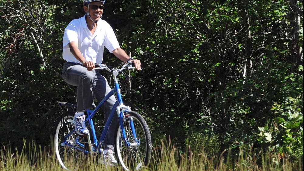US President Barack Obama rides his bicycle in West Tisbury on Martha's Vineyard, Massachusetts, on Aug. 27, 2010.