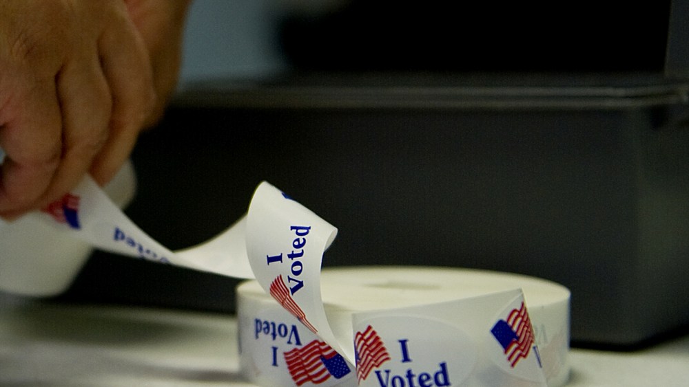 A voter peels off an "I Voted" sticker after casting her ballot at a polling station. (Photo by Jim Watson/AFP/Getty)