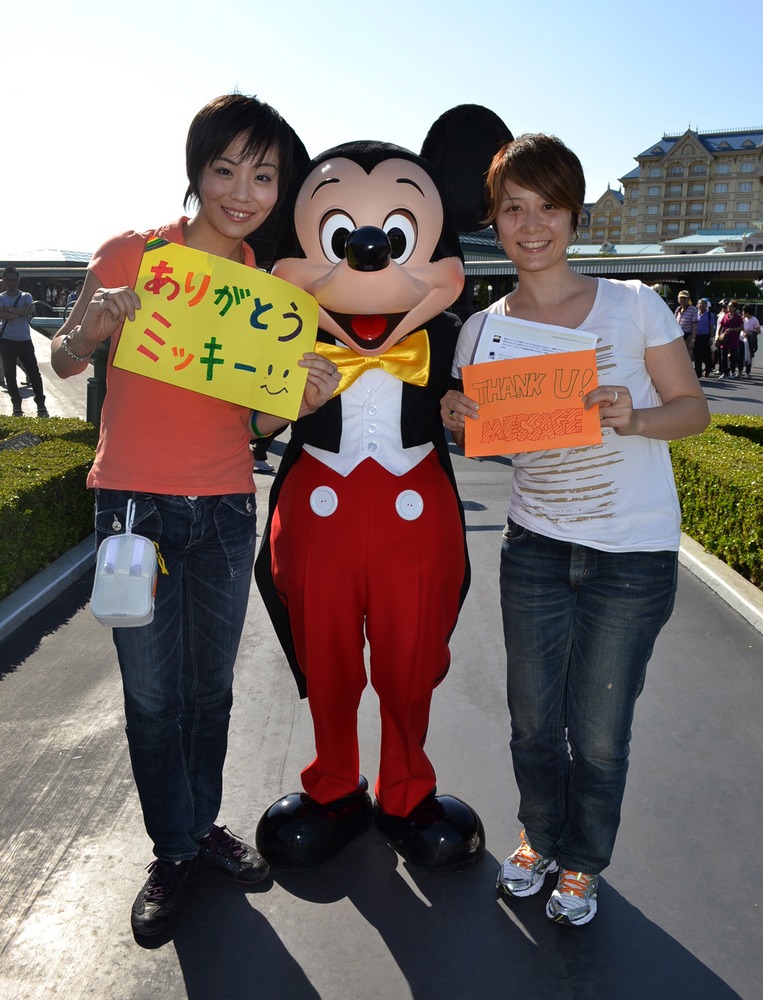 Koyuki Higashi (L) and her partner Hiroko (R) display "Thank you" messages to Mickey Mouse at the Tokyo Disneyland in Urayasu, suburban Tokyo.