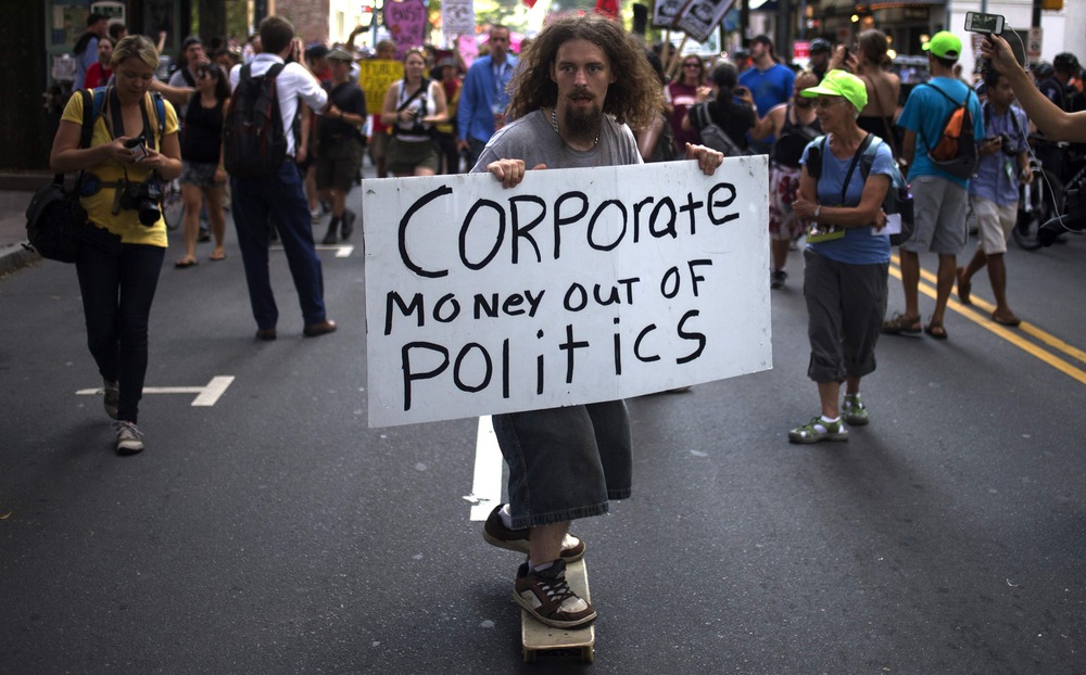 A demonstrator holds a placard while leading a protest from upon a skateboard through uptown Charlotte, the site of the Democratic National Convention in North Carolina on September 5, 2012.