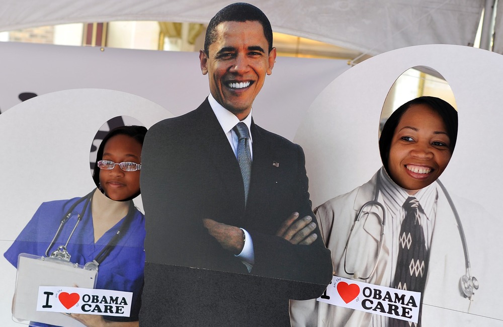 Two girls pose for a picture with a cardboard cut-out of  US President Barack Obama in a tent defending "Obamacare" at a street fair in Charlotte, North Carolina, September 3, 2012.
