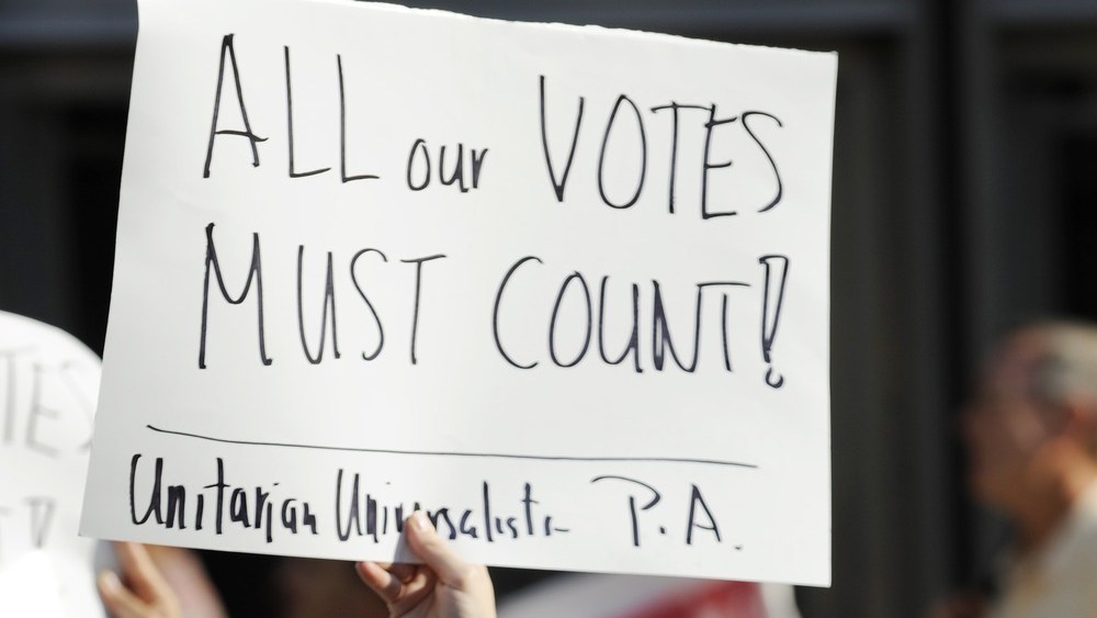 Emily Goldberg and her daughter Willa, 2, holds up a sign during the NAACP voter ID rally to demonstrate the opposition of Pennsylvania's new voter identification law, Thursday, September 13, 2012, in Philadelphia.