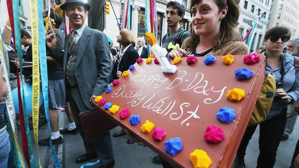 A protester affiliated with Occupy Wall Street holds a sign fashioned as a birthday cake on September 17, 2012, in New York City, the one year anniversary of the movement.