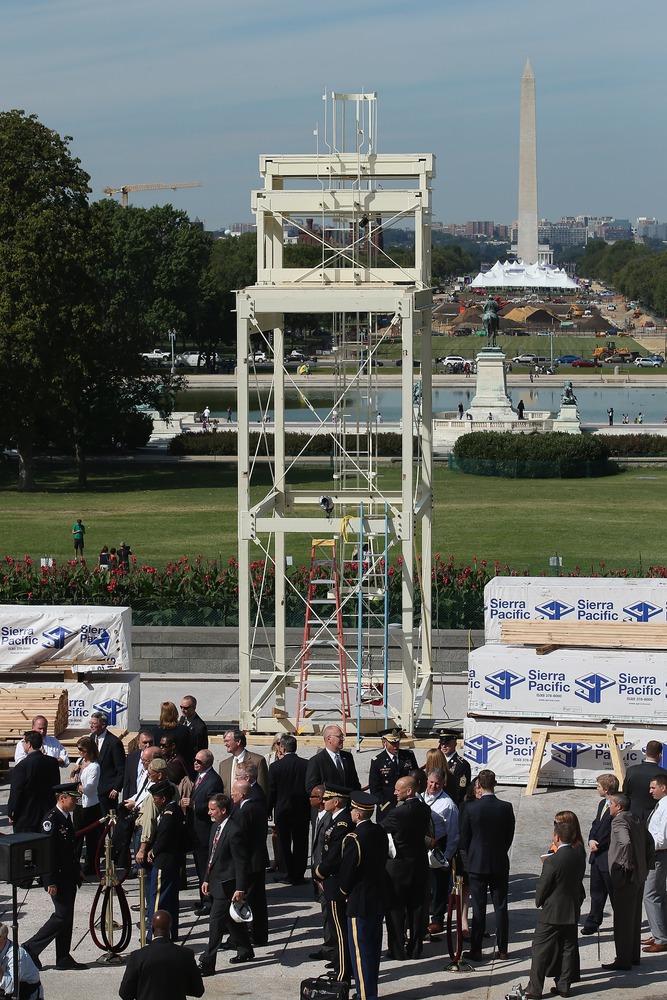 Officials and members of the news media gather at the base of the center camera platform during the 