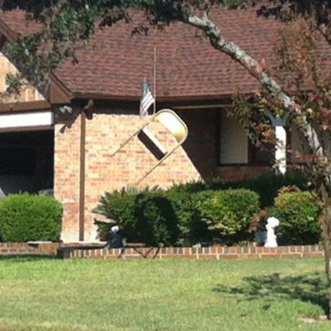 A folding chair and an American flag hang from a tree in front of a home in northwest Austin, Texas.