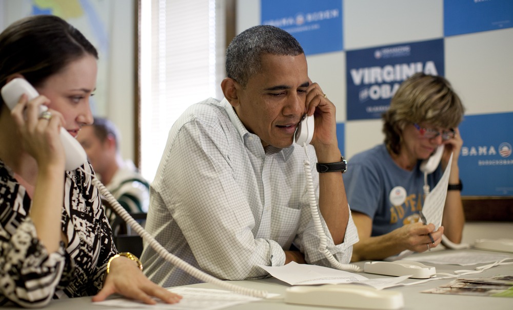 President Barack Obama makes phone calls to volunteers at an Organizing for America field office with Alexa Kissinger, left, and, Suzanne Stern, right,  Sunday, Oct. 14, 2012, in Williamsburg, Va.