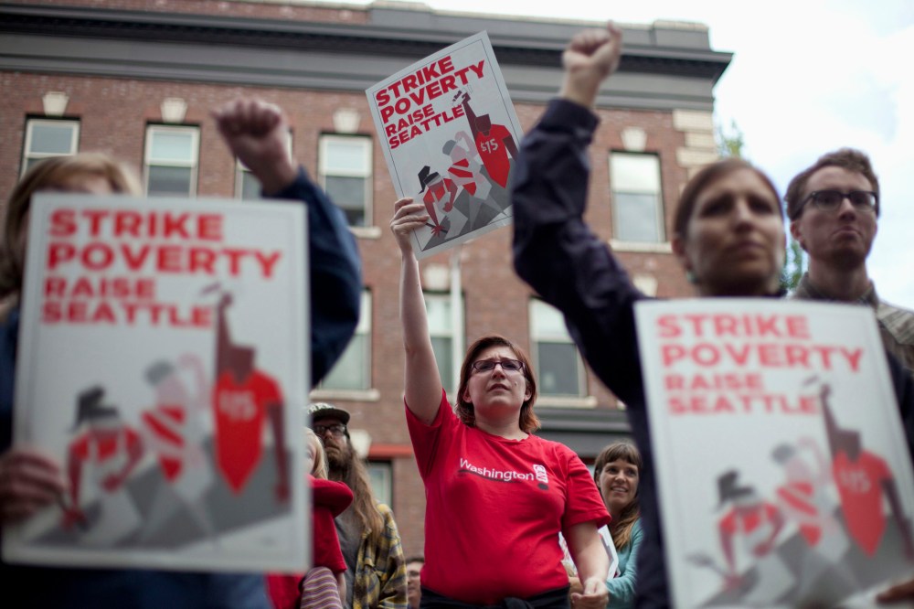 Joelle Craft (C) holds a sign during a rally and strike aimed at the fast-food industry and the minimum wage in Seattle, Washington August 29, 2013.