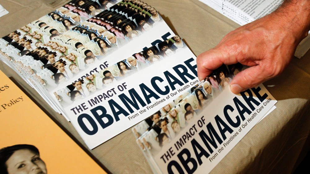 A Tea Party member reaches for a pamphlet titled "The Impact of Obamacare", at a "Food for Free Minds Tea Party Rally" in Littleton, New Hampshire in this October 27, 2012. (Photo by Jessica Rinaldi/Reuters)