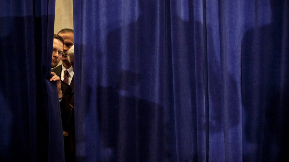Security peeks through a curtain before Republican presidential candidate, former Speaker of the House Newt Gingrich arrived for a party on primary night January 10, 2012 in Manchester, New Hampshire.